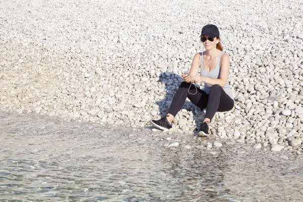 Sporty woman sitting on the beach — Φωτογραφία Αρχείου