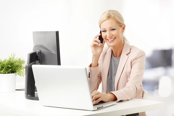 Mulher fazendo chamada enquanto sentado no escritório — Fotografia de Stock