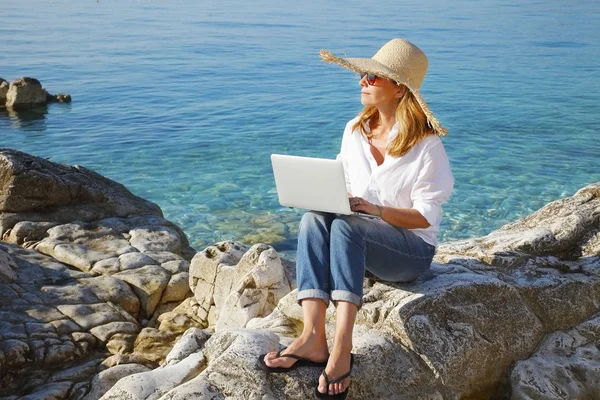 Business woman sitting by sea and working — Stock Photo, Image