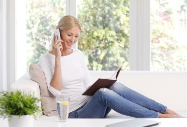 woman making call while sitting on sofa