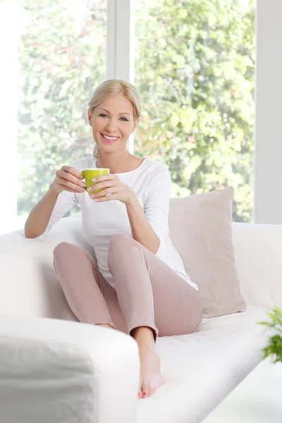 Femme relaxante au canapé tenant une tasse de thé — Photo