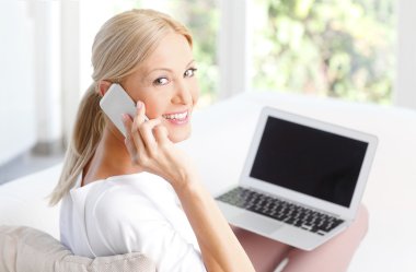 woman at home using mobile and laptop