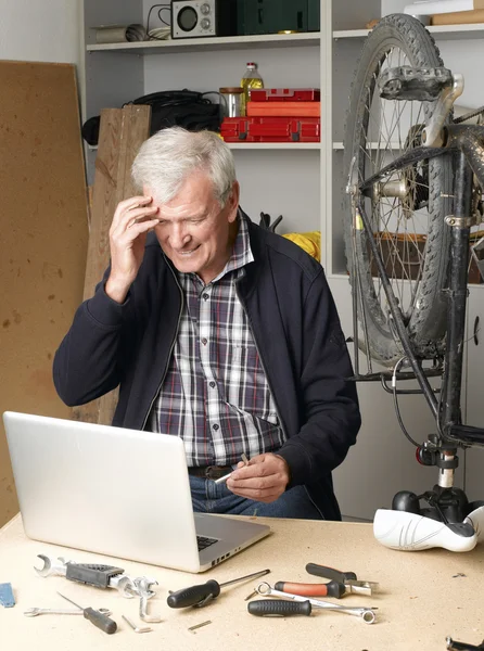 Senior bike shop owner in front of computer — Stock Photo, Image