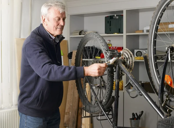 Man standing at workshop and repairs bike — Φωτογραφία Αρχείου