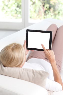 Tablet kullanarak koltukta oturan kadın