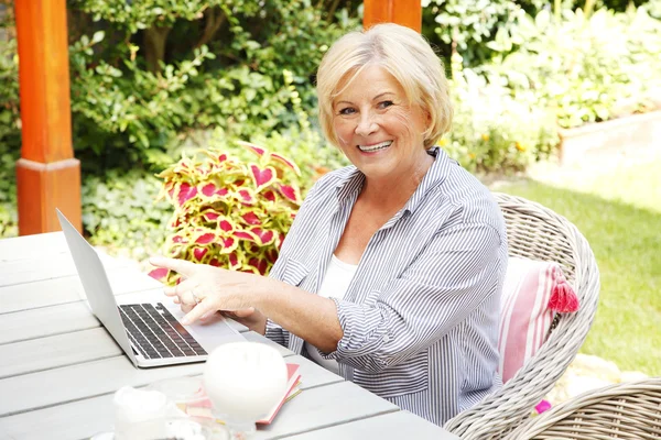 Senior kvinna med bärbar dator hemma — Stockfoto