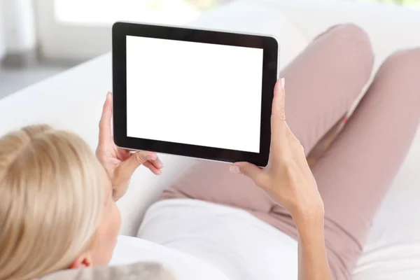 Kvinna sitter på soffan använder tablet — Stockfoto