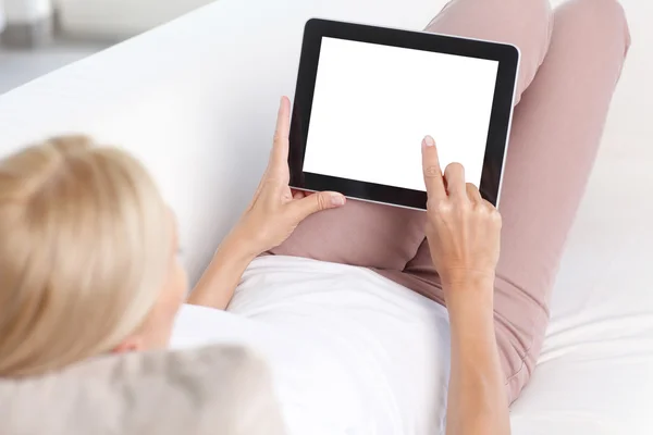 Kvinna sitter på soffan använder tablet — Stockfoto