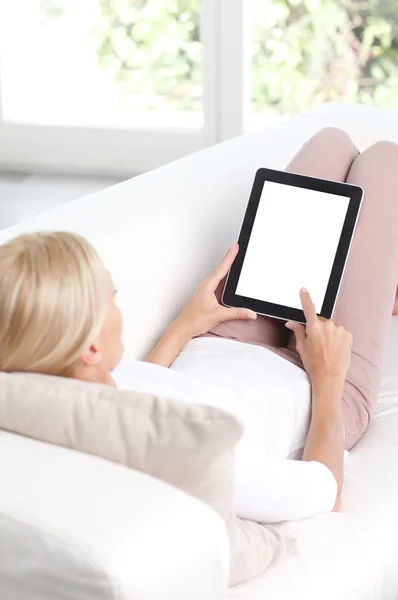 Femme assise sur un canapé et utilisant une tablette — Photo