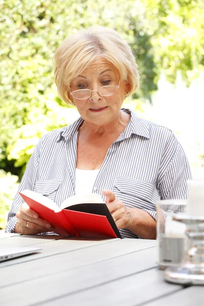 Senior kvinna läser en bok. — Stockfoto