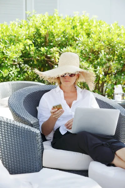 Жінка в саду працює онлайн з ноутбуком — стокове фото