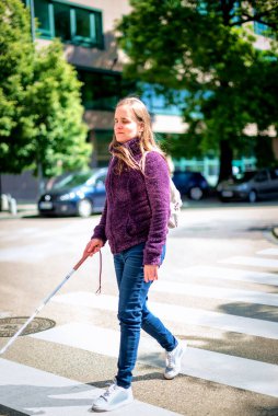 Beyaz bastonlu görme engelli bir kadın yaya geçidinden geçiyor. Tam boy çekim. 