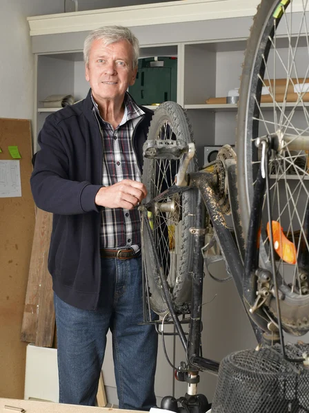 Bike shop owner repairs bicycle — Stockfoto