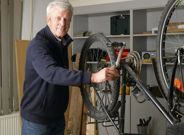 Bike shop owner repairs bicycle — Stock Photo, Image