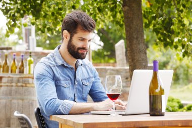 winemaker at wine cellar in front of laptop clipart