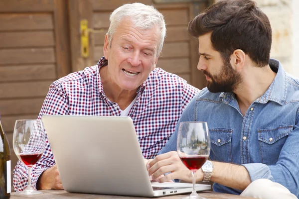Homens jovens e seniores degustando vinho tinto — Fotografia de Stock
