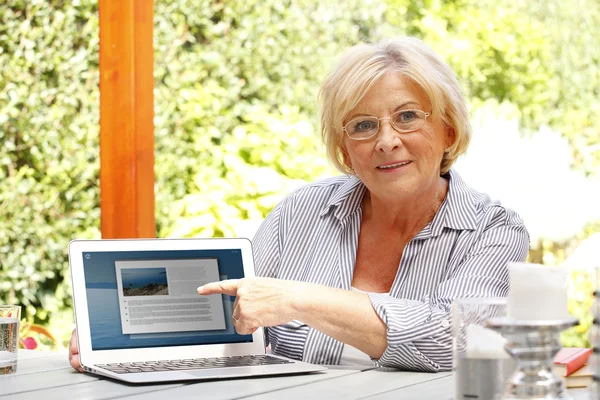 Kvinna i trädgården framför laptop — Stockfoto