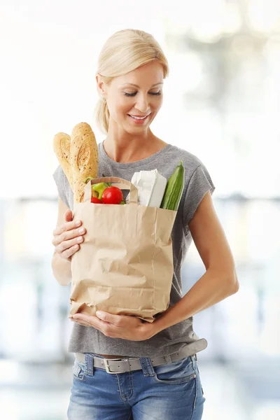 woman holding paper bag full of foods