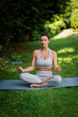 Orta yaşlı kadın arka bahçede tek başına yoga yapıyor. Tam yol ileri. Kendine güvenen, spor kıyafetleri giyen ve evdeki bahçede yoga yapan bir kadın. Tam uzunluk.