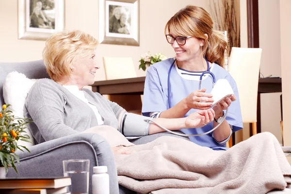 Woman sitting at home while nurse — Stock Photo, Image