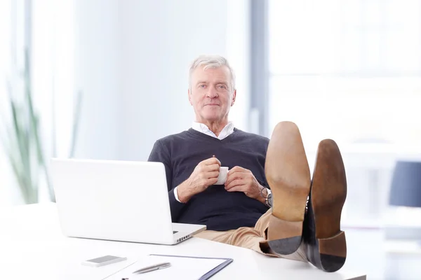 Businessman with legs on desk — Stock Photo, Image