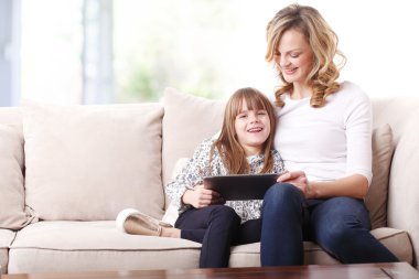 mother and daughter holding tablet