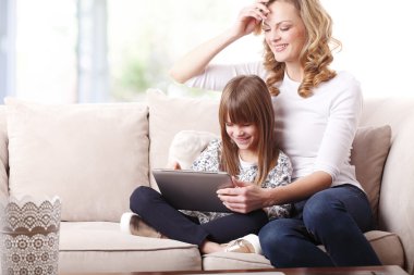 Happy mother and daughter holding tablet