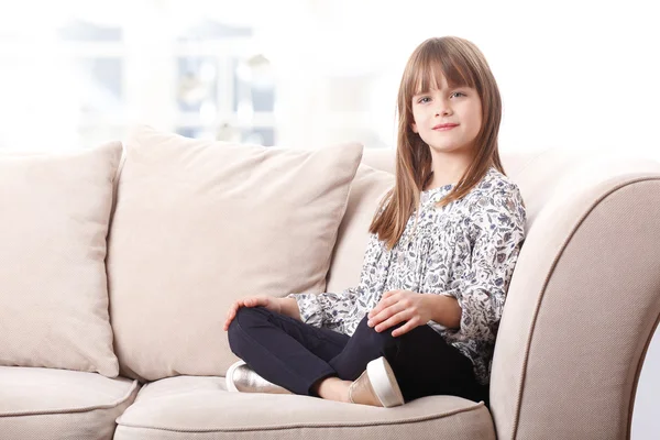 Aranyos lány ül a kanapén — Stock Fotó