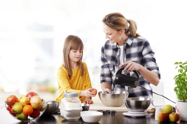 Meisje en moeder mengen van de ingrediënten. — Stockfoto