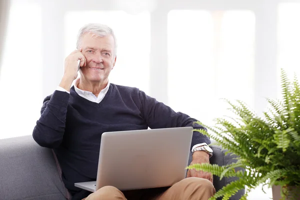 Senior sitzt zu Hause und arbeitet — Stockfoto