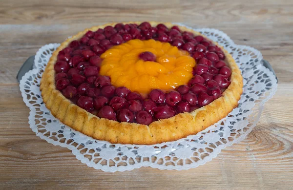 Gâteau aux fruits aux cerises et mandarines sur bois rustique — Photo