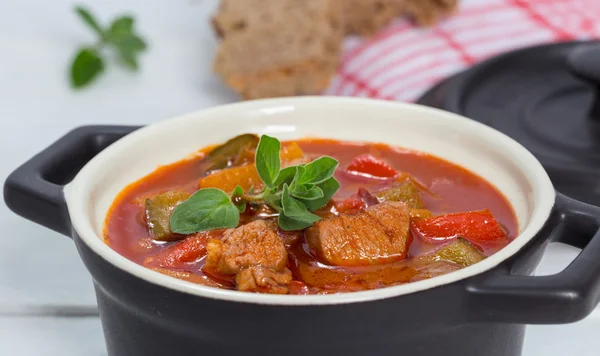 Gulaş ile mercanköşk beyaz tahta üzerinde siyah bir cocotte — Stok fotoğraf