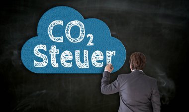 İşadamı tebeşirle karbon tahtasına CO2 Steuer (Almanca karbon vergisi) çiziyor.