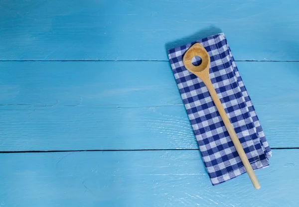 Wooden spoon and kitchen towel on blue wooden background — Stock Photo, Image