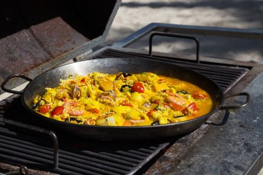 Paella is cooked on a grill clipart