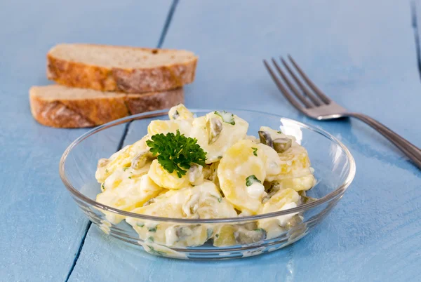 Potato salad in a glass bowl on wooden board — Stock Photo, Image