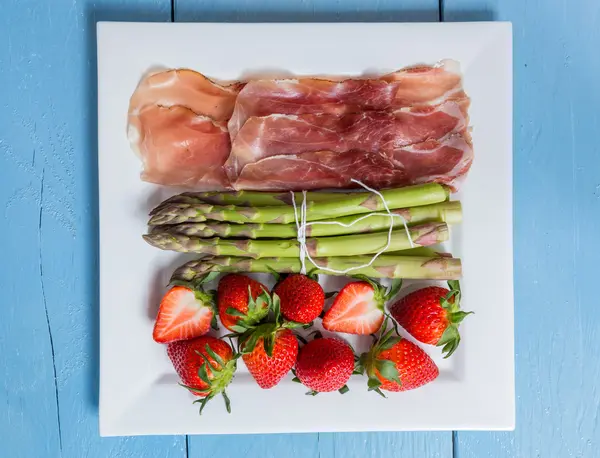 Green asparagus with ham and strawberries — Stock Photo, Image