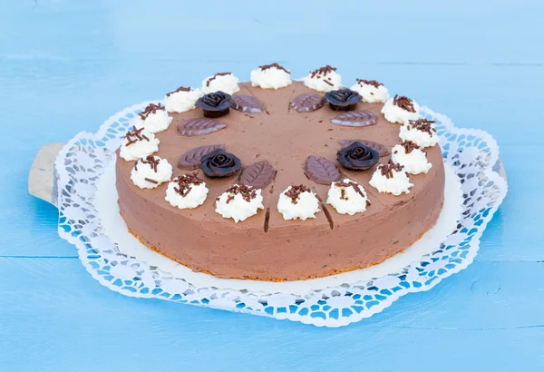 Chocolate cream cake on blue wood with cake lace — Stock Photo, Image