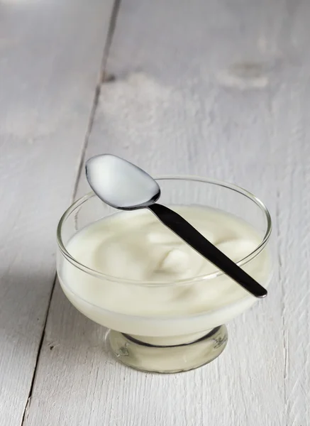 Natural yoghurt in glass with spoon on wood — Stock Photo, Image