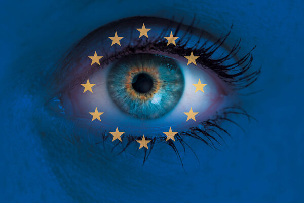 Eye looks through Europe flag background concept macro