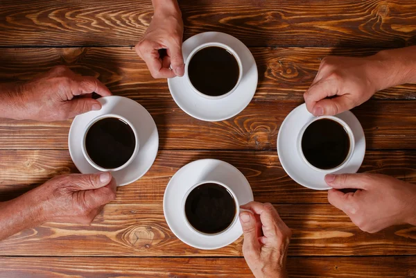 Una famiglia di quattro persone, che prende un caffè al vecchio tavolo di legno — Foto Stock