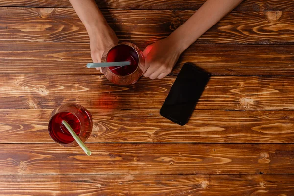 Femme relaxante dans un café avec cocktail rouge et un nouveau smartphone — Photo