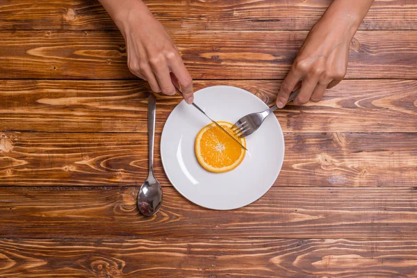 Chica está cortando naranja en el plato, concepto de dieta de frutas, vista superior —  Fotos de Stock