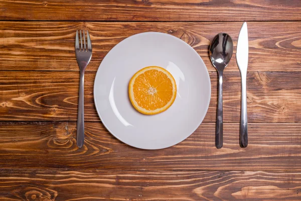 Fetta d'arancia in un caffè su un piatto bianco con posate — Foto Stock