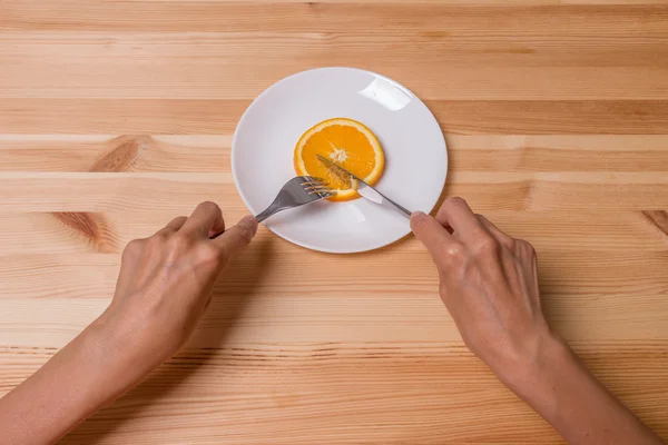 La donna sta tagliando arancione sul piatto, concetto di dieta di frutta — Foto Stock