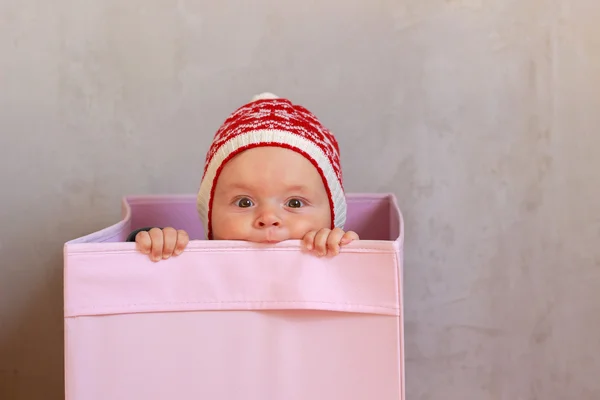 Cute little baby in winter hat surprise stares from pink boxes — Stock Photo, Image