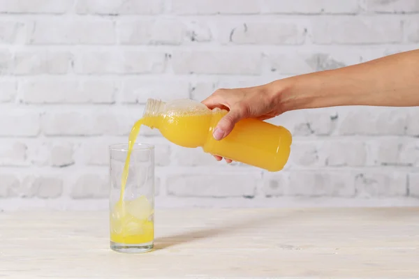 Young girl pouring juice into glass with ice on white table — Stock Photo, Image