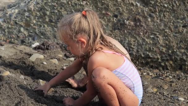 Petite sœur mignonne jouant sur la plage avec du sable — Video