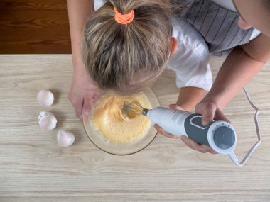 Anne küçük kızına pasta yapmayı öğretiyor.