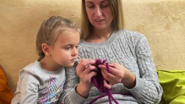 Genç anne küçük kıza örgü örmeyi öğretiyor. — Stok video